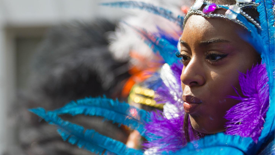 Close-up of dancer's face wearing blue and purple feathered head dress