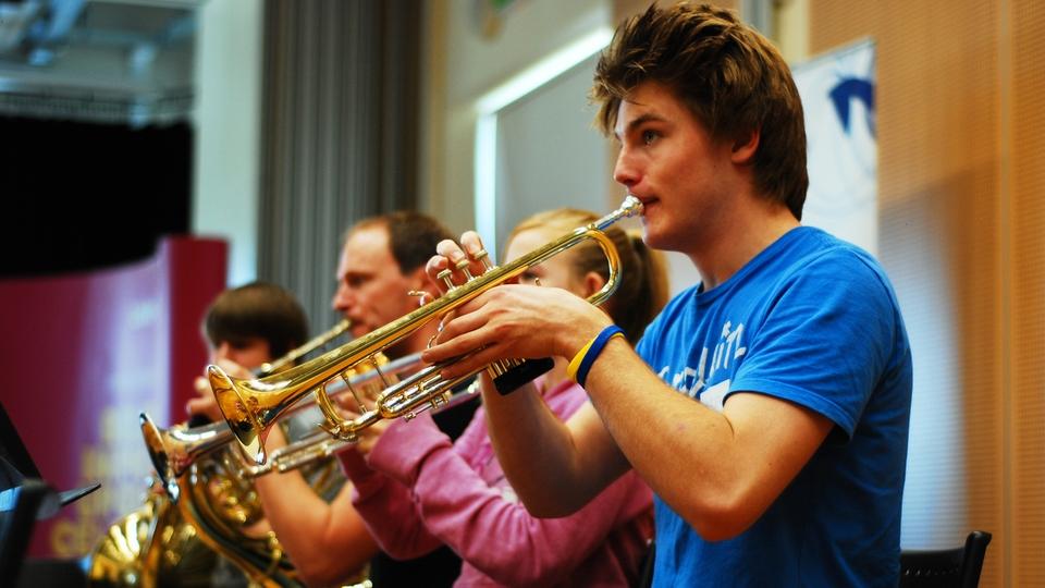 Four musicians play trumpets in rehearsals