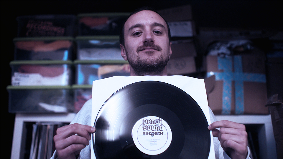 Bearded man holds up a vinyl record