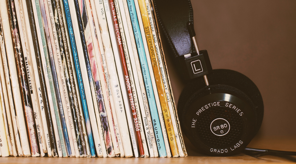 A pair of headphones leaning on a rack of LPs. 