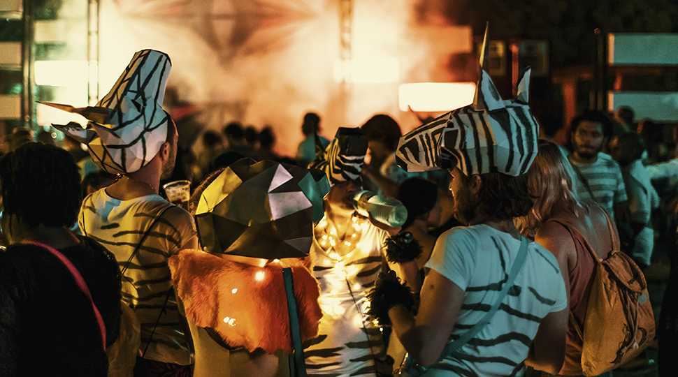 Festival goers dressed as zebras in front of brightly lit music stage