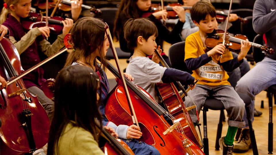 Young children play various string instruments 