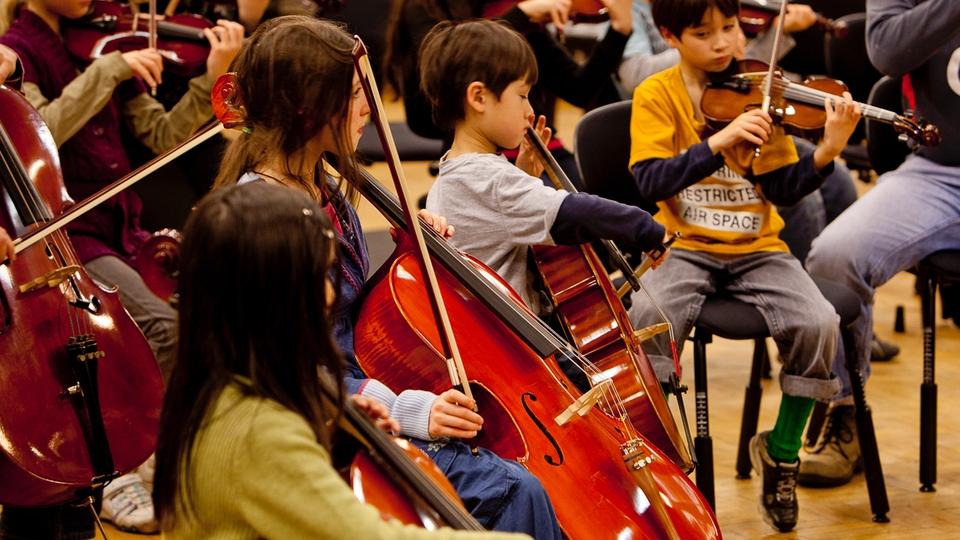 Young children play various string instruments