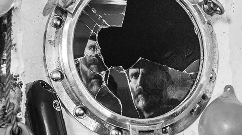 Man's reflection shattered in broken porthole - a still from Bait film