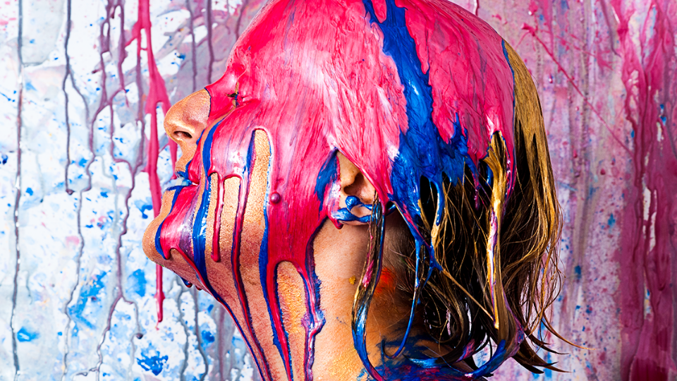 Close up on face with multi-coloured paint dripping down