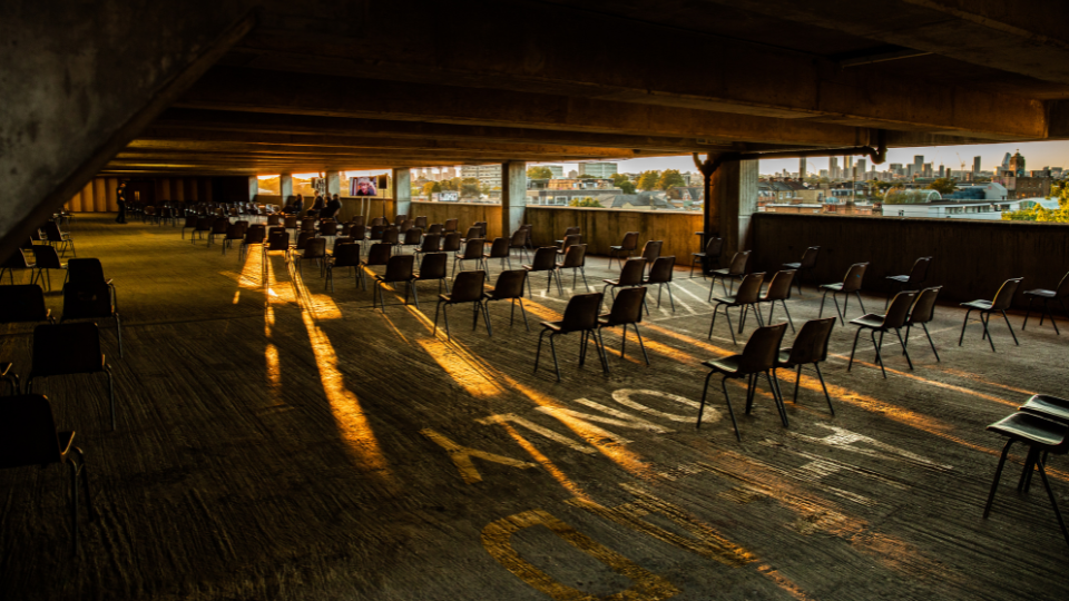 Inside a car park without cars and rows of chairs set out like a theatre.